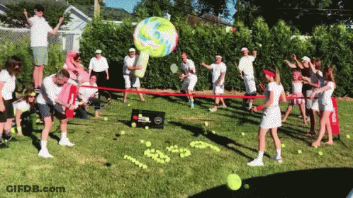 A Group Of People Are Playing A Game Of Tennis In A Grassy Area GIF