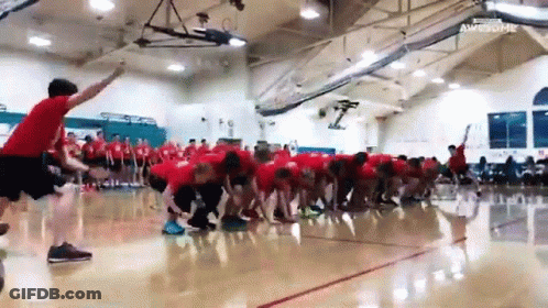 A Group Of People Are Playing A Game Of Tug Of War In A Gym . GIF