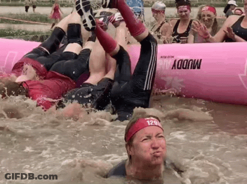 A Group Of People Are Playing In A Muddy Pool With A Pink Raft That Says Muddy On It GIF