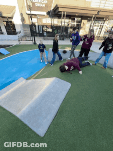 A Group Of People Are Playing In A Park In Front Of An American Dream Store GIF