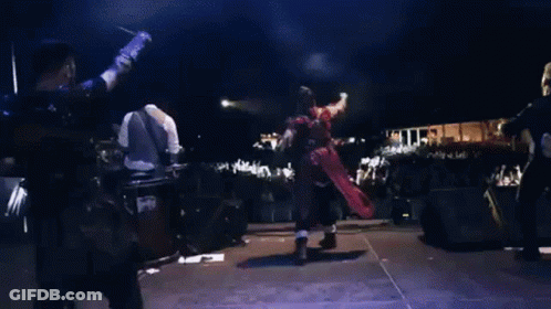 A Group Of People Are Playing Instruments On A Stage In Front Of A Large Crowd GIF