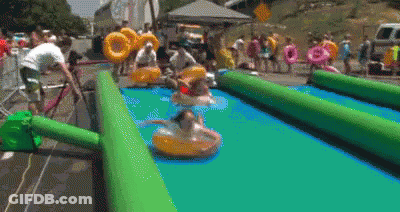 A Group Of People Are Playing On A Water Slide With Tubes . GIF