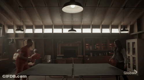 A Group Of People Are Playing Ping Pong In A Dark Room With A Sign That Says Global On It GIF