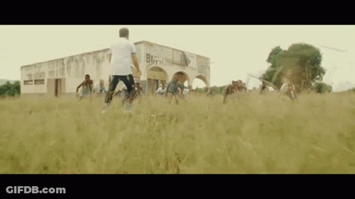 A Group Of People Are Playing Soccer In A Field In Front Of A Building That Has The Word Born On It GIF