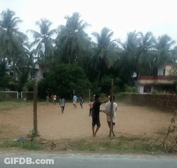 A Group Of People Are Playing Volleyball On A Dirt Field With Palm Trees In The Background GIF