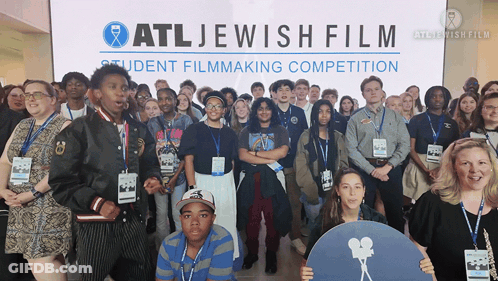 A Group Of People Are Posing For A Picture In Front Of A Sign That Says Atl Jewish Film GIF