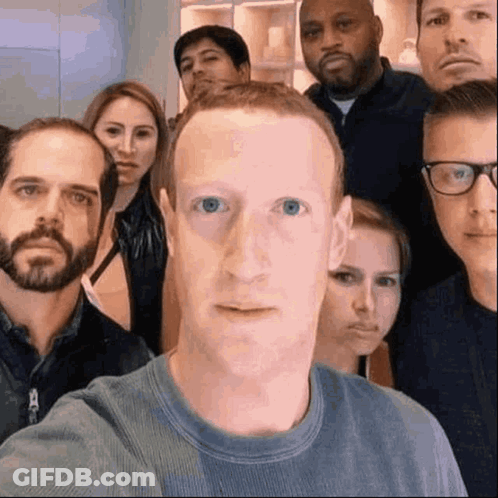 A Group Of People Are Posing For A Picture With A Man In The Middle Making A Face . GIF
