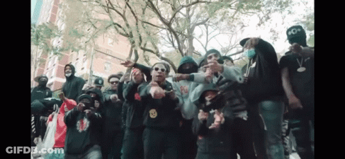 A Group Of People Are Posing For A Picture With One Wearing A Hoodie With A Smiley Face On It . GIF