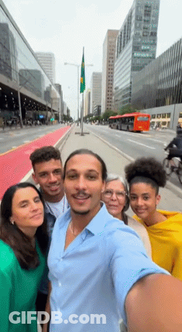 A Group Of People Are Posing For A Selfie In Front Of A City Street GIF