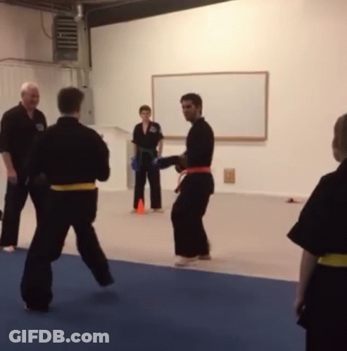 A Group Of People Are Practicing Martial Arts In Front Of A Whiteboard GIF
