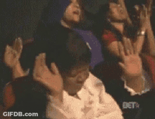 A Group Of People Are Raising Their Hands In The Air With Bet In The Background GIF