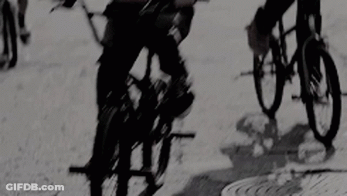 A Group Of People Are Riding Bikes Down A Street . GIF