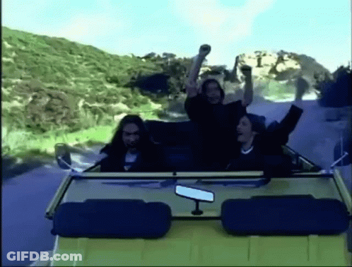 A Group Of People Are Riding In A Convertible Car On A Road . GIF