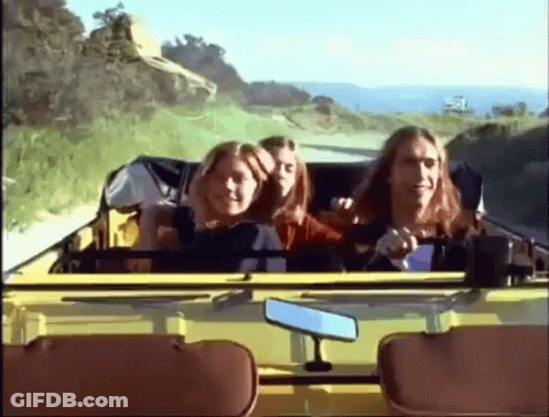 A Group Of People Are Riding In A Yellow Car On A Country Road GIF