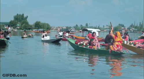 A Group Of People Are Riding In Boats On A Lake GIF