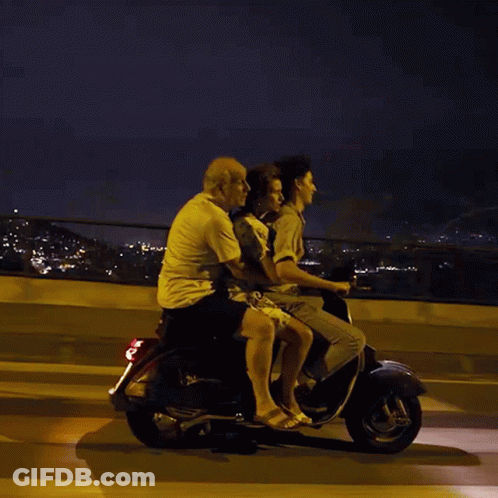 A Group Of People Are Riding On A Scooter At Night GIF