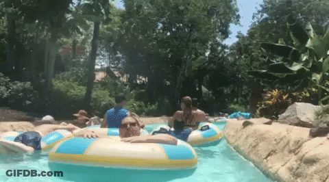 A Group Of People Are Riding Rafts Down A Water Slide . GIF