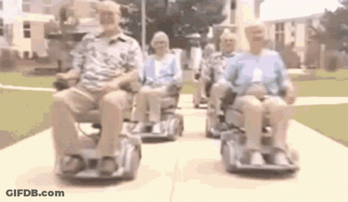A Group Of People Are Riding Scooters Down A Sidewalk . GIF