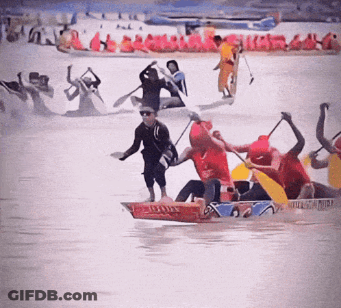 A Group Of People Are Rowing Boats In The Water And One Of Them Is Wearing A Shirt That Says ' Red Bull ' On It GIF