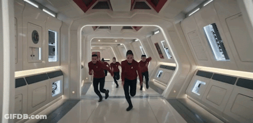 A Group Of People Are Running Down A Hallway In A Spaceship . GIF