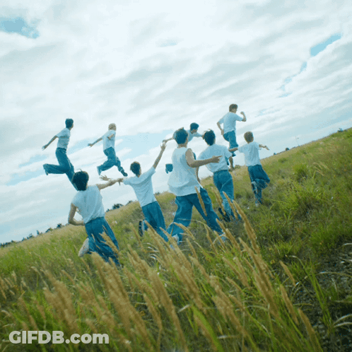 A Group Of People Are Running In A Field With Their Arms Outstretched GIF