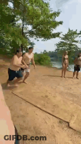 A Group Of People Are Running On A Dirt Road . GIF