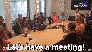 A Group Of People Are Sitting Around A Conference Table And They Are Saying Let 'S Have A Meeting . GIF