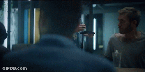 A Group Of People Are Sitting Around A Table And One Man Is Holding A Bottle Of Water GIF