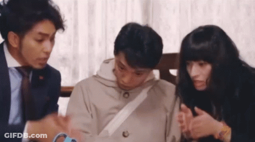 A Group Of People Are Sitting Around A Table Talking . GIF