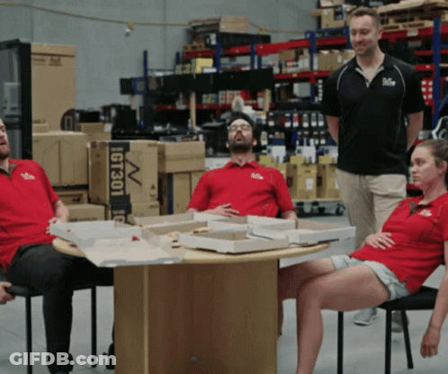 A Group Of People Are Sitting Around A Table With Boxes Of Pizza And A Sign That Says Gt301 GIF