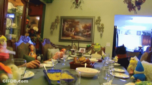 A Group Of People Are Sitting Around A Table With Plates And Glasses GIF