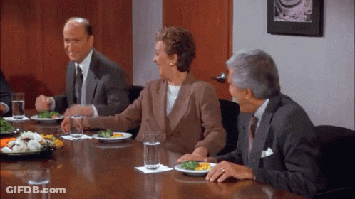 A Group Of People Are Sitting Around A Table With Plates Of Food And Glasses Of Water . GIF