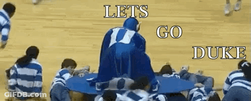 A Group Of People Are Sitting Around A Table With The Words Let 'S Go Duke On The Bottom GIF
