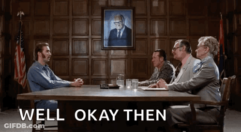 A Group Of People Are Sitting Around A Table With The Words Well Okay Then Written On The Bottom GIF