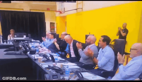 A Group Of People Are Sitting At A Table Clapping GIF
