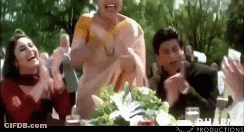 A Group Of People Are Sitting At A Table Clapping And Laughing GIF