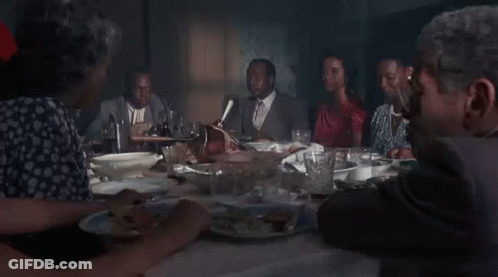 A Group Of People Are Sitting At A Table Eating Food . GIF