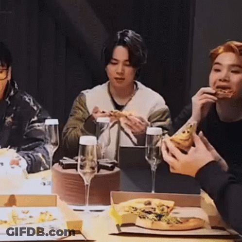 A Group Of People Are Sitting At A Table Eating Pizza And Wine Glasses . GIF