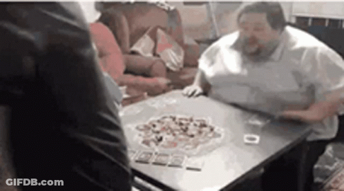 A Group Of People Are Sitting At A Table Playing A Game Of Cards . GIF