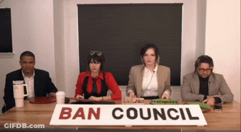 A Group Of People Are Sitting At A Table With A Sign That Says Ban Council GIF