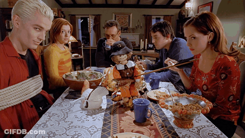 People Sitting At Table With Stuffed Pilgrim GIF