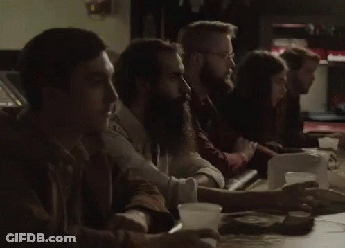 A Group Of People Are Sitting At A Table With Cups In Their Hands GIF