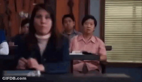 A Group Of People Are Sitting At Desks In A Classroom In Front Of A Window . GIF