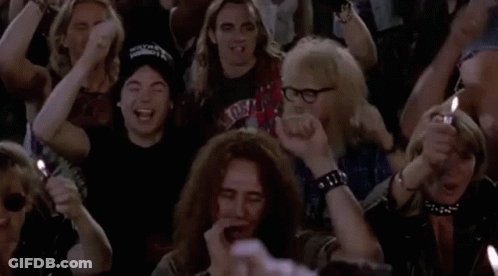 A Group Of People Are Sitting In A Crowd Holding Candles And Lighter . GIF