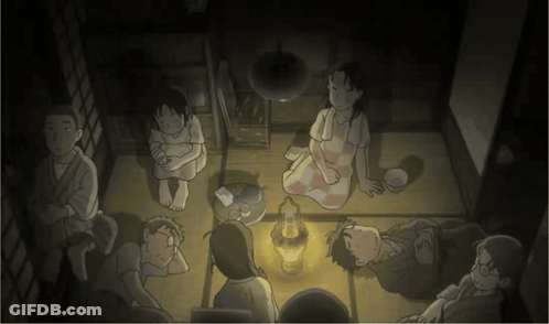A Group Of People Are Sitting In A Dark Room With A Lantern In The Middle GIF