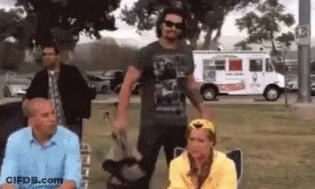 A Group Of People Are Sitting In A Park With A White Truck In The Background . GIF