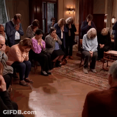 A Group Of People Are Sitting In A Room And Praying GIF
