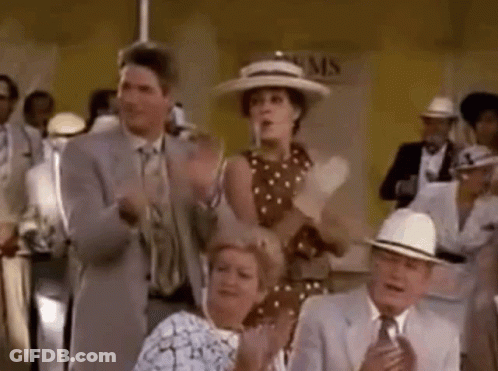 A Group Of People Are Sitting In A Room Clapping Their Hands In A Crowd . GIF