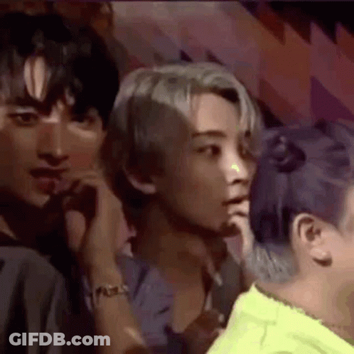 A Group Of People Are Sitting In A Room Talking To Each Other . One Of The People Has Purple Hair . GIF