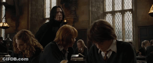 A Group Of People Are Sitting In A Room With A Man In A Black Suit Standing Behind Them GIF